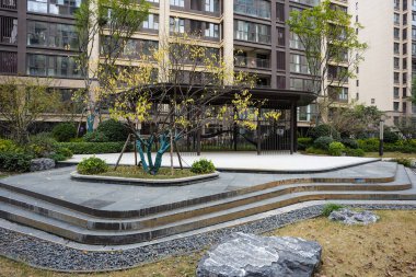 Zarif eğimli taş basamakların ve sakin bir avluda dekoratif çakılların arkasına yerleştirilmiş çağdaş karanlık metal dinlenme köşkü. Görüntü sakin bir mahalleyi ve şık bir açık hava yaşamını temsil ediyor. Yüksek kaliteli gerçek fotoğrafçılık