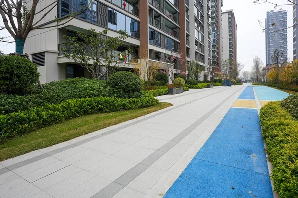 Çevrili kaldırımlı kaldırım yolu ve peyzajlı bir halk bahçesinde dolanan mavi koşu yolu. Görüntü kentsel zindelik ve sağlıklı yaşam sağlıyor. Doğal ışıklandırmalı yüksek kaliteli gerçek fotoğrafçılık.