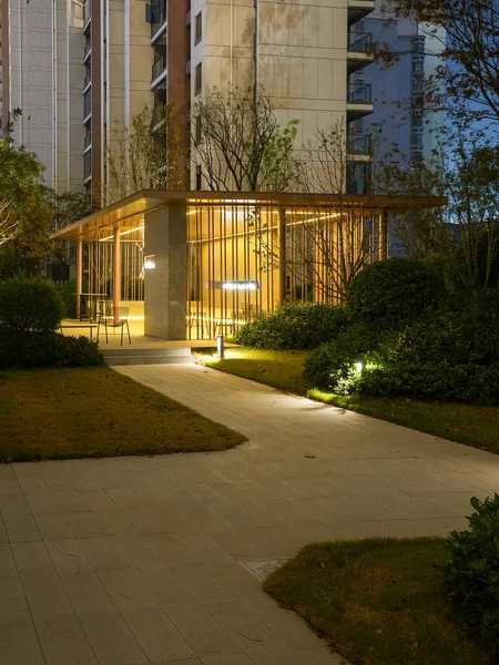 Kavisli taş yürüyüş yolu, alacakaranlıkta huzurlu bir halk bahçesinde sıcak bir dinlenme yerine doğru gidiyor. Görüntü güvenli bir mahalle ve hoş geldin ortamı sağlıyor. Doğal ışıklandırmalı yüksek kaliteli gerçek fotoğrafçılık.