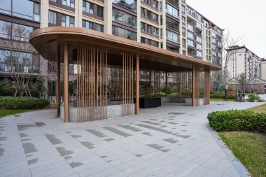 Uçsuz bucaksız bir çarşaf üzerinde eğimli bir çatı ve dikey tahta levhalar bulunan zarif modern topluluk pavyonu. İmaj, mimari zarafet ve lüks mahalle konforları sunuyor. Doğal ışıklandırmalı yüksek kaliteli gerçek fotoğrafçılık.