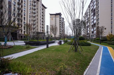 Kavisli taş kaldırım ve mavi boyalı koşu yolu modern yerleşim yerlerinde yeşil çimlerin yanında. Görüntü aktif yaşam tarzını ve sağlıklı şehir yaşamını aktarıyor. Doğal ışıklandırmalı yüksek kaliteli gerçek fotoğrafçılık.