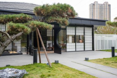 Şebeke pencereleri ve manikürlü bir çam ağacının yanında dairesel sürgülü kapıları olan sakin bir avluda modern doğu tarzı bir pavyon. Görüntü, ahenkli bir yaşam ve zarif bir mimari tasarım sunuyor. Yüksek kaliteli gerçek fotoğrafçılık.