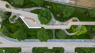 Güzel manzaralı bir konut bahçesinin hava aracı görüntüsü, taş yollar, yeşil çimenler ve modern pavyon yapılarını gösteriyor. İmaj konut uyumu, toplum planlaması, mimari denge ve yeni şehir yaşamını aktarıyor. Yüksek Kalite