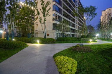 Güzel, aydınlık bir bahçe yolu gece yerleşim bölgesinde, huzurlu bir yürüyüş ortamı sunuyor. Görüntü şehir uyumu, akşam eğlencesi, konut tasarımı ve sakin bir atmosfer taşır. Sığ derinliğe sahip yüksek kaliteli gerçek fotoğrafçılık