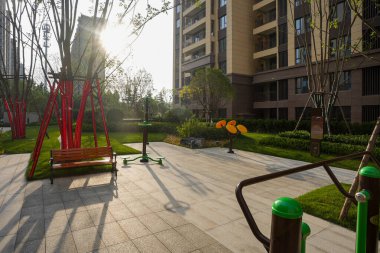 Canlı bir bahçe spor salonu, spor aletleri ve bir bank, sıcak öğleden sonra güneşiyle yıkanmış. Görüntü, sağlık, etkinlik, açık hava sağlığı ve huzur dolu bir yaşam sunuyor. Sığ alan derinliğine sahip yüksek kaliteli gerçek fotoğrafçılık.