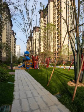 Olgun ağaçlarla çevrili, çocuk parkına giden temiz taş yolu olan huzurlu bir apartman bahçesinin yüksek açılı görüntüsü. İmaj, toplumsal barışı, modern kentsel yaşamı, refahı ve doğal güzelliği taşır. Yüksek kaliteli gerçek fotoğrafçılık ile Will