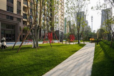 Parlak, geniş bir bahçe manzarası modern bir oyun parkı olan parkın içinden geçen iyi korunmuş bir taş yolu gösteriyor. Görüntü açık alan, toplum uyumu, huzurlu günlük yaşam ve peyzaj tasarımı taşır. Sığ d ile yüksek kaliteli gerçek fotoğrafçılık