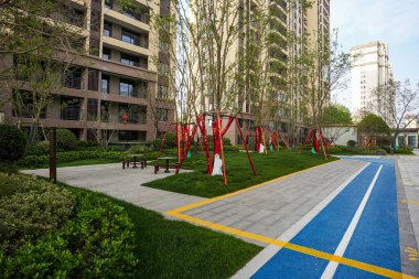 Canlı bir mavi pist ve manikürlü yeşil çimlerin yer aldığı, temiz ve düzenli bir açık alan sağlayan manzaralı bir yerleşim alanı. Resim, toplum eğlencesi, huzurlu bahçe ortamı, modern tasarım ve etkinlik taşır. Yüksek kalite gerçek