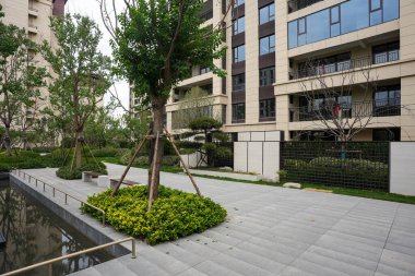 Yansıyan bir gölet, taş kaldırım ve modern bahçe duvarı olan manzaralı bir yerleşim yeri. Görüntü meditasyon, yapısal uyum, doğa bütünleşmesi ve huzur dolu bir yaşam sunuyor. Sığ alan derinliğine sahip yüksek kaliteli gerçek fotoğrafçılık.