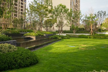 Yeşil bir çimenliğin güzel, geniş manzarası ve sakin bir bahçe parkında katmanlı su manzarası. Görüntü dinginliği, doğa bağlantısını, lüks yaşamı ve mimari dengeyi taşır. Sığ derinlikli yüksek kaliteli gerçek fotoğrafçılık