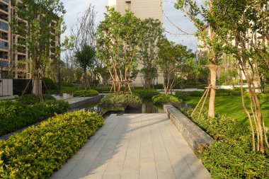 Yansıtıcı bir su havzası olan, yemyeşil bir bahçe parkından geçen sakin bir taş geçit. Görüntü doğa bütünleşmesini, mimari düzeni, barışı ve açık hava atmosferini aktarıyor. Kaliteli gerçek fotoğrafçılık ve sığ bir derinlik.