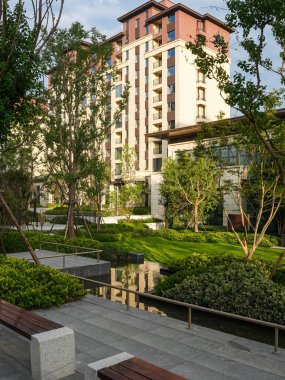 Güzel, geniş manzaralı, taştan merdivenleri, yansıyan bir göleti ve apartmanlara karşı yüksek ağaçları olan modern bir konut bahçesi. Görüntü meditasyondaki dinginliği, mimari tasarımı, lüksü ve huzurlu günlük yaşamı aktarıyor. Yüksek kalite r