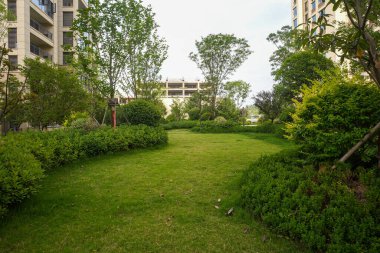 Olgun ağaçlar ve yerleşim alanındaki manikürlü çalılarla dolu yeşil bir bahçeden geçen sakin, dolambaçlı bir taş yol. Görüntü doğal sükuneti, tasarım düzenini, barışçıl yürüyüşü ve şehir yeşilliğini aktarıyor. Yüksek kaliteli gerçek fotoğrafçılık ile Will