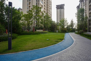 Canlı bir mavi egzersiz pisti ve ağaçlarla çevrili sakin yeşil çimlere sahip modern bir bahçe. Görüntü aktif toplum yaşamını, tasarım yeniliklerini, renkli ayrıntıları ve barışçıl açık alanı taşır. Yüksek kalite gerçek ph