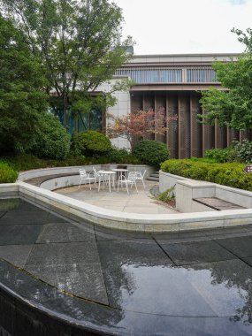 Beyaz mobilyaları, taş kaldırımları ve modern bir konut bahçesinde sakin bir su havzası olan rafine edilmiş bir açık alan. Görüntü, sofistike toplum hayatını, tasarım dengesini, lüksü ve huzurlu günlük yaşamı aktarıyor. Yüksek kaliteli gerçek fotoğraf.