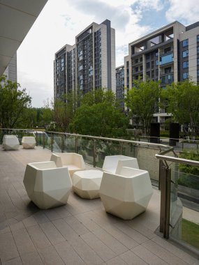 Soyut, heykel koltuklu rafine bir açık alan. Huzurlu bir yeşil alana bakan modern bir güverteye kurulmuş. Görüntü lüks yaşam tarzını, tasarım karmaşıklığını, huzuru ve üst düzey dış tasarımı aktarıyor. Yüksek kalite gerçek pho