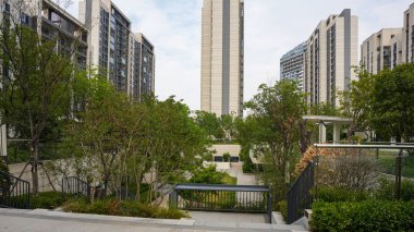 Güneşli bir bahçe parkı modern apartman mimarisi, ağaçlar ve peyzaj yolları için açık bir manzara sunuyor. Görüntü toplum huzurunu, kentsel tasarımı, tazeliği ve üst düzey doğa yaşamını aktarıyor. Şallo ile yüksek kaliteli gerçek fotoğrafçılık