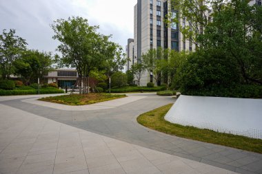 Beyaz, modern bahçe duvarları ve delikli detaylarla dolu bir yerleşim parkından geçen temiz bir taş patika. Görüntü mimari dengeyi, huzurlu günlük yaşamı ve son model peyzajı aktarıyor. Sığ ve yüksek kaliteli gerçek fotoğrafçılık