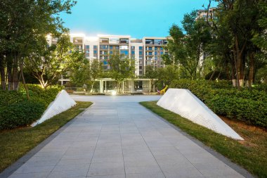 Modern beyaz mimari duvarlar ve temiz taş bir patika içeren güzel, geniş bir plazanın akşam manzarası. Bu resim toplum uyumu, açık alan, mimari tasarım ve huzurlu günlük yaşamı taşır. Yüksek kaliteli gerçek fotoğrafçılık zekası.