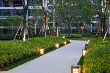 Akşam geçişi sırasında sıcak, düşük seviyeli bahçe ışıklarıyla kaplı sakin bir taş yol. Görüntü güvenliği, akşam sükunetini, açık hava yaşam tarzını ve konforlu atmosferi sağlar. Sığ alan derinliğine sahip yüksek kaliteli gerçek fotoğrafçılık.