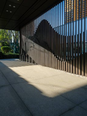 Metal bir ızgaranın içinden asfalt bir yola düşen güneş ışığının etkileşimi. Görüntü, soyutlamayı, mimari havayı ve zamanın kamusal alanda geçişini aktarır. Yüksek kaliteli gerçek fotoğrafçılık..