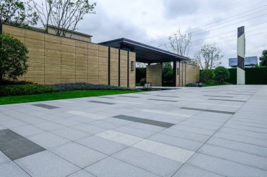 Açıklama: gündüz boyunca boş, taş kaplı bir duvar ve plaza alanı. Görüntü, mimari alanda minimalist tasarım, düzen ve sükunet hissi taşır. Yüksek kaliteli gerçek fotoğrafçılık..