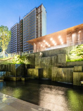 Akşamları modern bir gökdelene basamaklı bir şelale sergileniyor. İmaj, şehir vahasını, mimari ölçeği ve sofistike tasarımı taşır. Yüksek kalite fotoğrafçılık.