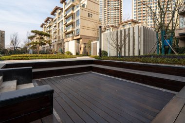 Tarifi: peyzajlı bir yerleşim alanı içindeki ahşap bir güverte alanı. Görüntü, park boş zamanlarını, mimariyi ve modern bahçe tasarımını aktarıyor. Yüksek kalite fotoğrafçılık.