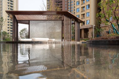 Tarif: Peyzaj yapılmış bir parktaki sakin bir gölete yansıyan modern bir pavyon. Görüntü, Zen dinginliğini, mimarisini ve barışçıl doğasını aktarıyor. Yüksek kalite fotoğrafçılık.