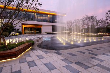 Tarif: Modern bina ve alacakaranlıkta ışıklar olan bir çeşme manzarası. Görüntü, gece mimarisi, tasarım ve açık hava sükunetini aktarıyor. Yüksek kalite fotoğrafçılık.