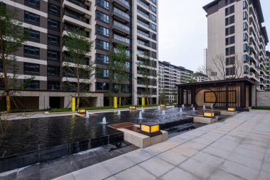 Tarifi: küçük su çeşmeleri ve sıcak akşam ışıkları olan bir bahçe meydanı. Görüntü, mimari ruh hali, tasarım ve kentsel dinginliği aktarır. Yüksek kalite fotoğrafçılık.