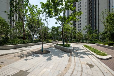 Tarif: Modern asfaltlı ve yemyeşil ağaçlı peyzaj manzaralı bir yerleşim yeri. Görüntü şehir yeşilliğini, tasarımı ve doğayı taşır. Yüksek kalite fotoğrafçılık.