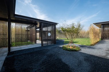 Tarif: Güneşli bir günde taştan yolu ve yemyeşil ağaçları olan huzurlu bir Zen bahçesi. Görüntü mimariyi, doğayı ve barışçıl tasarımı taşır. Yüksek kalite fotoğrafçılık.