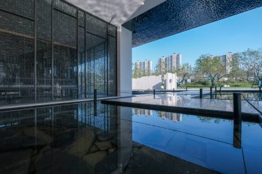 Açıklama: Bir dinlenme odasının içinden su birikintisine ve mimariye bakan bir manzara. Görüntü lüks, tasarım ve dingin mimari içerir. Yüksek kalite fotoğrafçılık.