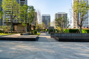 Tarif: Modern bir şehir parkı ortamında temiz taş kaldırımları ve manzaralı ağaçlarla dolu geniş bir plaza. Görüntü mimari tasarım, dinginlik ve kentsel alan taşır. Yüksek kalite fotoğrafçılık.