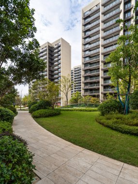 Çağdaş yüksek binalarla çevrili, gür, peyzajlı bir bahçe alanından geçen, taşlarla döşenmiş sakin bir yürüyüş yolu..