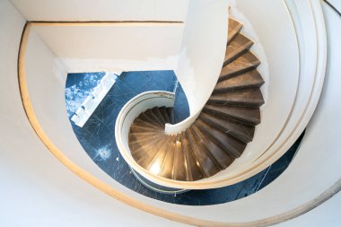 Modern bir binanın içindeki güzel, sarmal bir merdivene bakan yüksek açılı bir çekim. Temiz çizgiler ve mimari zarafet sergiliyor..