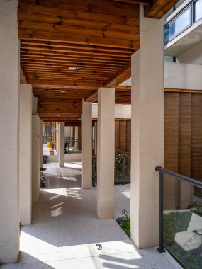 Modern bir binada minimalist bir koridor. Temiz beton hatları, ahşap tavan kirişleri ve açık hava manzarası var..