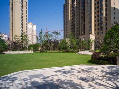 Şehir merkezinin yoğun apartman kulelerine karşı yeşil bir çimenliğin ölçeğini gösteren geniş, parlak bir manzara.