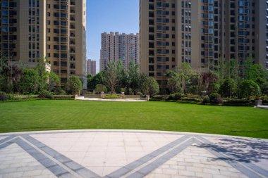 Geniş açılı geniş bir manzara. Manikürlü bir çimenlik. Temiz bir halk parkındaki uzun, modern apartman kuleleriyle çevrili..