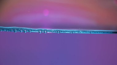 Mavi su yüzeyi boyunca pembe eğimli hava kabarcıkları, temiz sıvı doku, makro su altı çizgisi, tazelik kavramı..