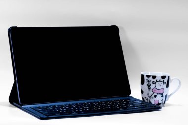 Çıkarılabilir klavyesi ve beyaz arka planda izole kahve fincanının yanında boş ekranı olan modern tablet. Web sitesi, uygulama veya iş tasarımı için kopya alanı olan çalışma alanı modellemesi.