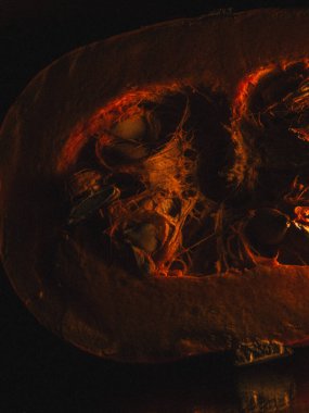 Bir balkabağının doğal dokusunu ve koyu arkaplandaki sıcak renk tonlarını vurgulayan yakın çekimi.