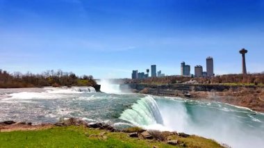 Ontario, Kanada, 9 Ağustos 2025: Güneşli bir günde kıyıdan Niagara Şelalesi 'nin manzarası. Ziyaretçiler Niagara Şelalesi 'nin yanında dururlar..