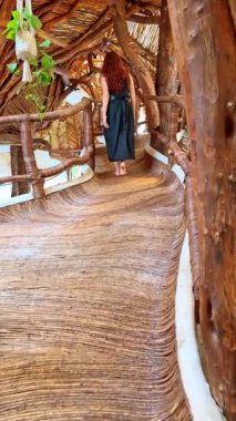 Tahta bir yapıda, patikada yürüyen bir kadın. Meksika 'da doğal bir binada, ağaçtan yapılmış kıvrımlı bir patika boyunca yürüyen bir kadın..