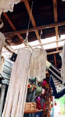 Bej pamuklu makrome iplikleri asmaya yakın durun. Düğümlü ve yıpranmış uçlu doğal pamuk iplerin dikey görünümü bulanık arkaplanda.