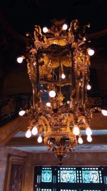 Boston, ABD, 5 Mayıs 2025 tarihi konağın büyük salonunda altın bir avize. Lüks bir Altın Çağ gayrimenkullerinin içinde parıldayan ampulleri olan eski, yaldızlı bir avizenin yakın çekimi..