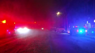 Bulanık acil durum ışıklarıyla karlı yolun zemin katı. Geceleri parlak kırmızı ve mavi ışık yansımalarıyla karla kaplı bir şehir yolunun alçak açılı perspektifi.