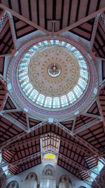 Valencia 'daki Merkez Market' teki kubbenin iç manzarası. Dekoratif metal yapısı ve çiçekli detaylarıyla cam bir kubbenin düşük açılı mimari görüntüsü.