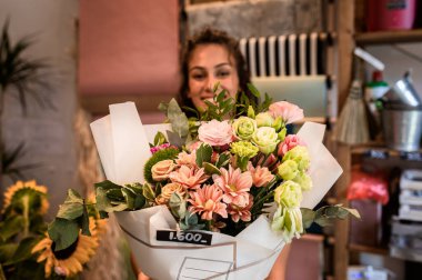 Çiçekçide elinde buket olan kadın çiçekçinin portresi.